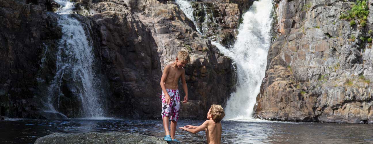 Barn som badar vid ett vattenfall.