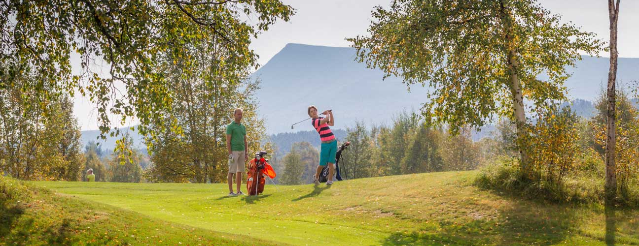 Två golfspelare med fjäll i bakgrunden.