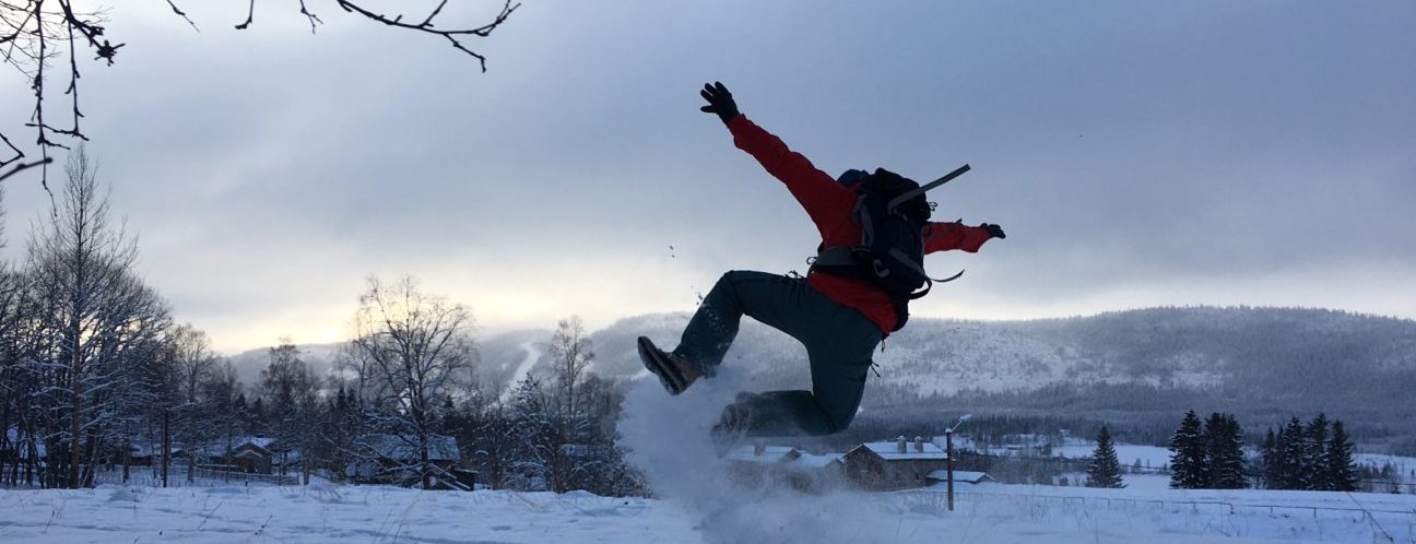 Man som hoppar i snön och gör ett hoppsasteg så att snön yr