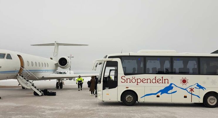 Buss, Fjällbuss står på flygplats bredvid mindre passagerarflygplan