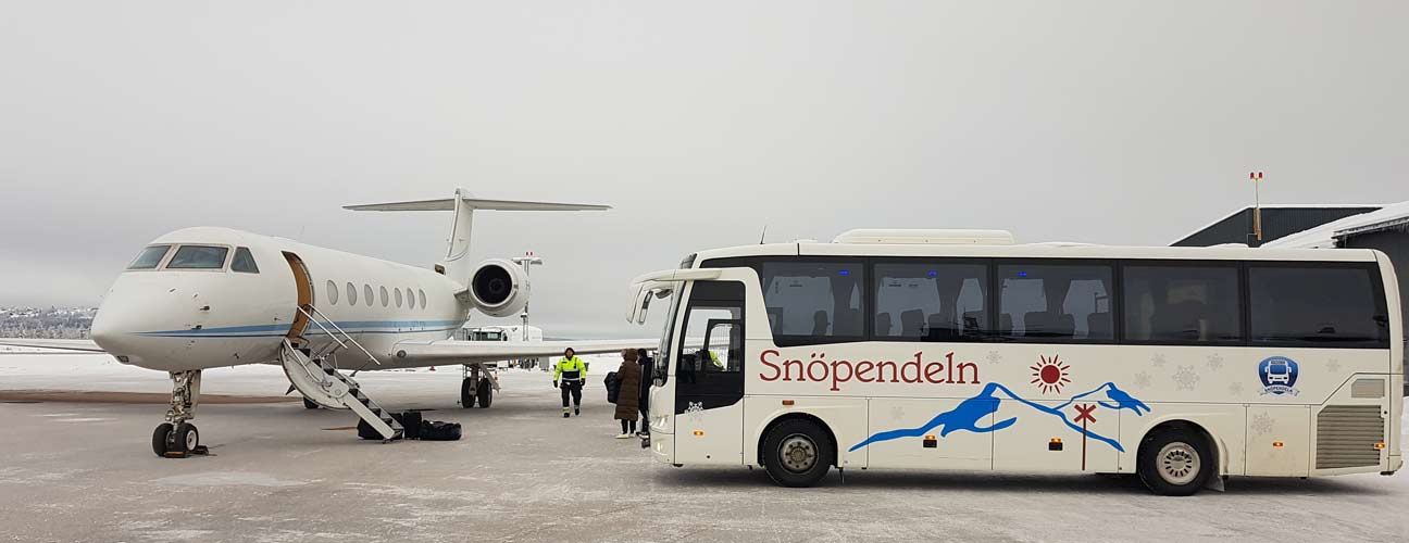 Buss, Fjällbuss står på flygplats bredvid mindre passagerarflygplan