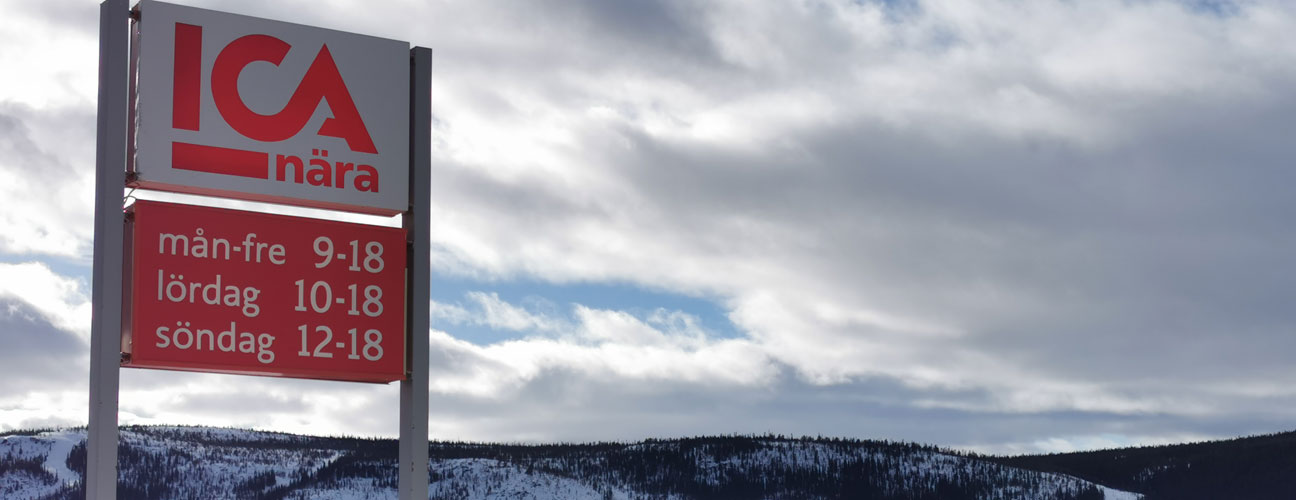Ica klövsjö-skylt som visar öppettider, vinterlandskap och moln i bakgrunden