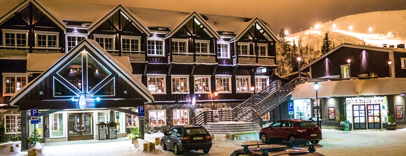 Fasadbild av Vemdalsskalets högfjällshotell under vintern, Natt och många upptända lampor.