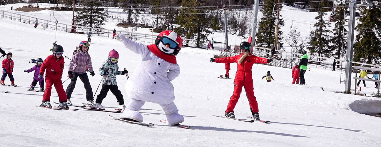 Snögubben Valle åker skidor tillsammans med några barn