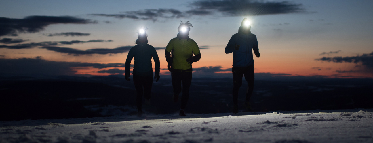 Löpare med pannlampa på fjället vintertid.