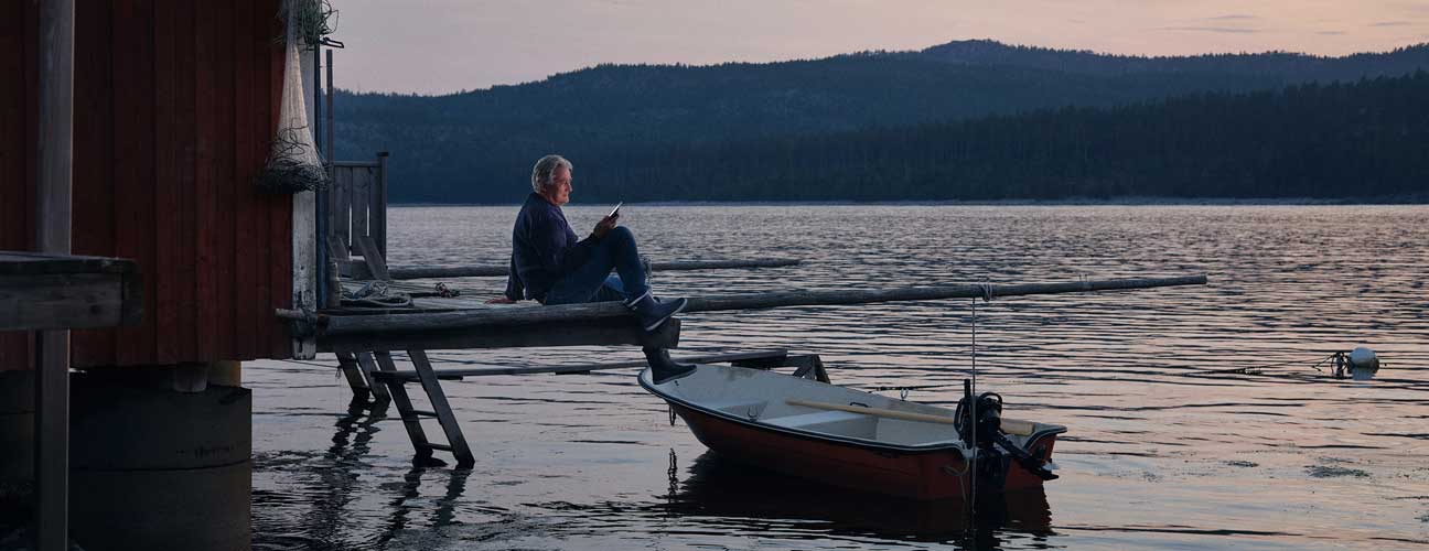 Äldre man sitter på brygga kvällstid. Härjeånskoncernen