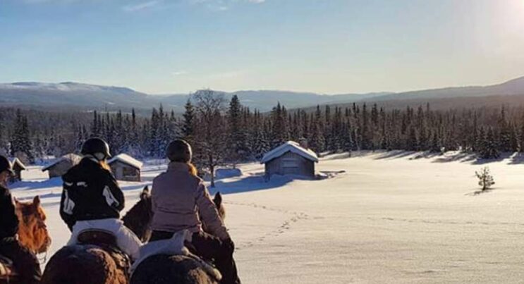 Trumvallen ute och rider häst i vintern, fjäll i bakgrunden