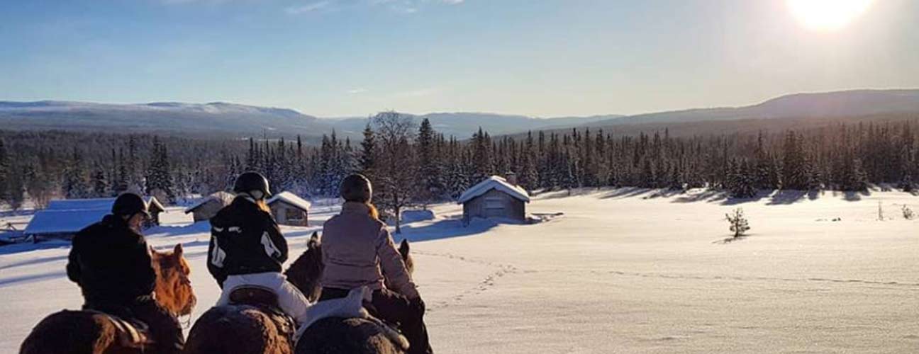 Trumvallen ute och rider häst i vintern, fjäll i bakgrunden