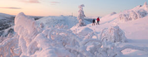 Par åker skidor upp för snötäckt fjällandskap