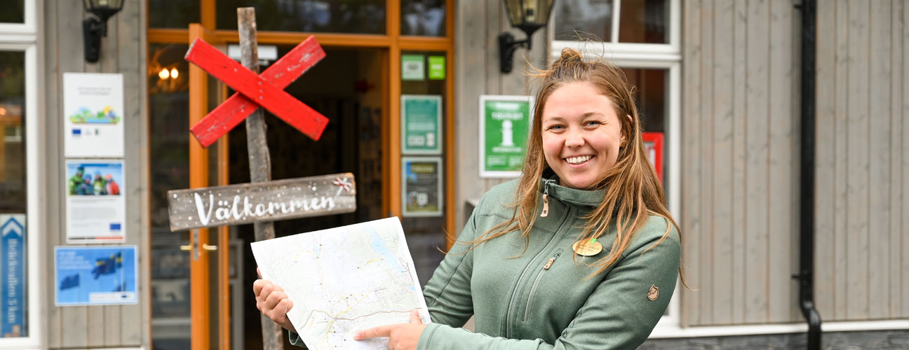 Turistinformatör står framför turistbyrån i Vemdalen och visar upp en karta