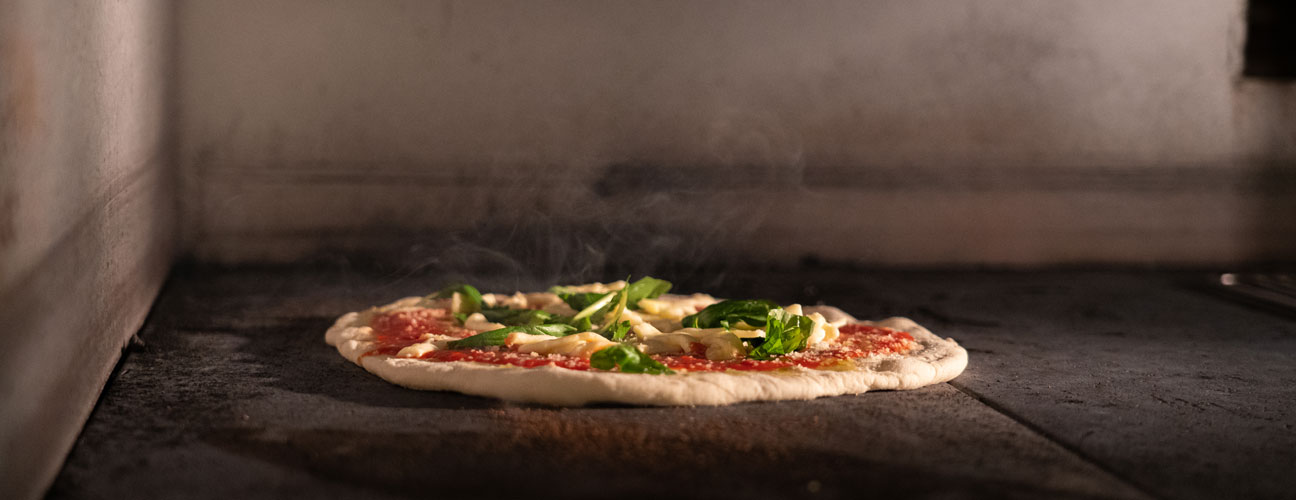 Rykande pizza tillagas i ugn